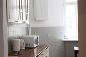 A kitchen with white cabinets, a microwave, and a window.