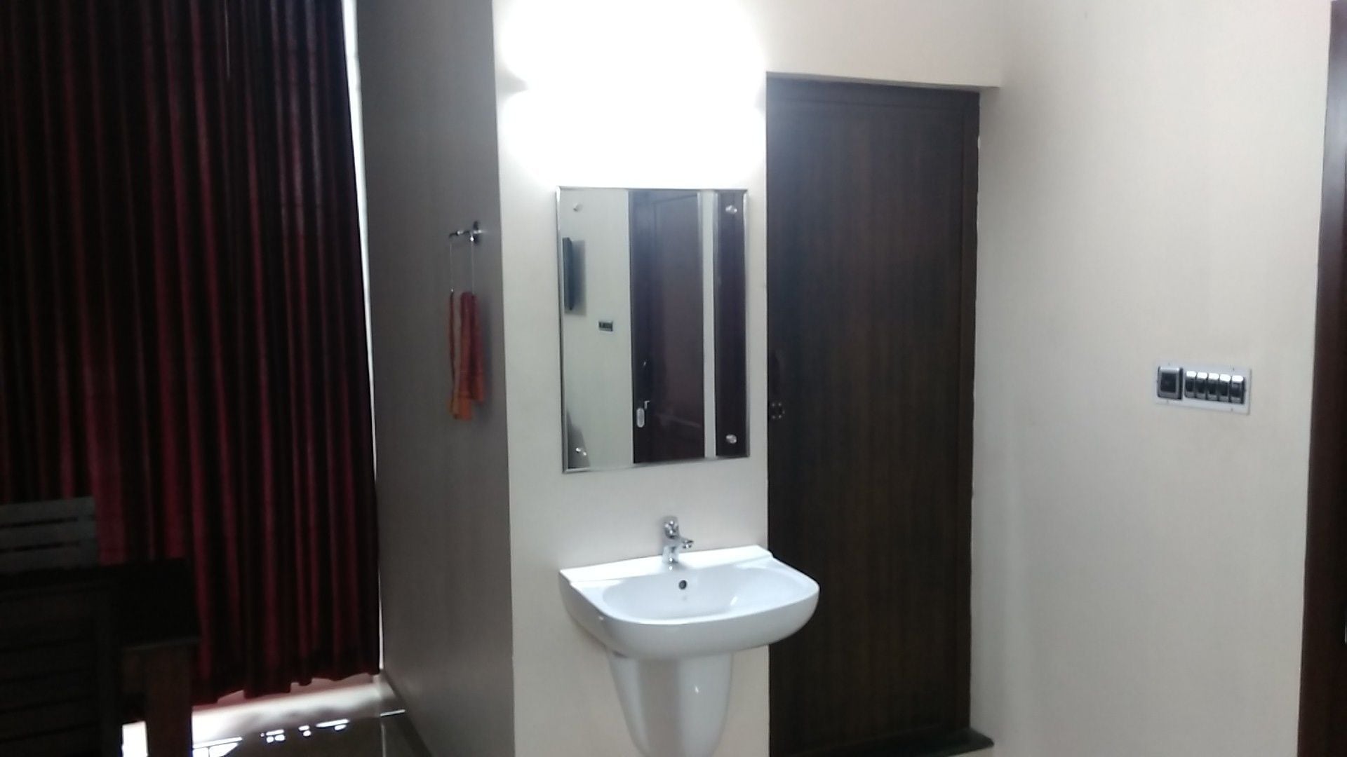 A bathroom with a white sink, a mirror, and a dark wooden door.