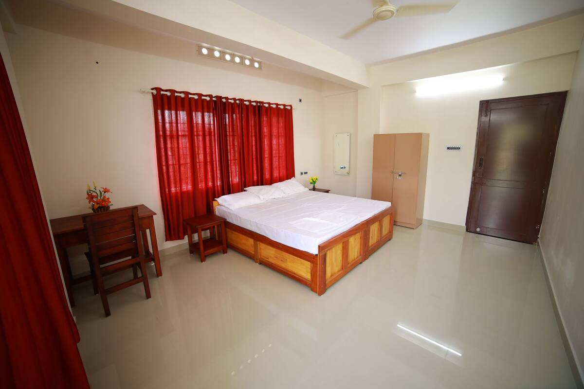 A bedroom with a wooden bed, a desk, a chair, a wardrobe, and a mirror.