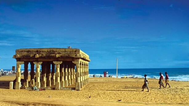 A historical stone structure with columns on a sandy beach, overlooking the sea. - Indeevaram Residency (Thiruvananthapuram)