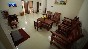 A living room with wooden furniture, a TV, and a painting on the wall. - Indeevaram Residency (Thiruvananthapuram)