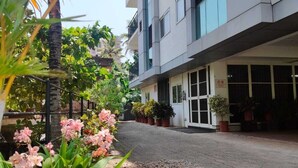 A paved street with potted plants and a building with a modern design. - Indeevaram Residency (Thiruvananthapuram)
