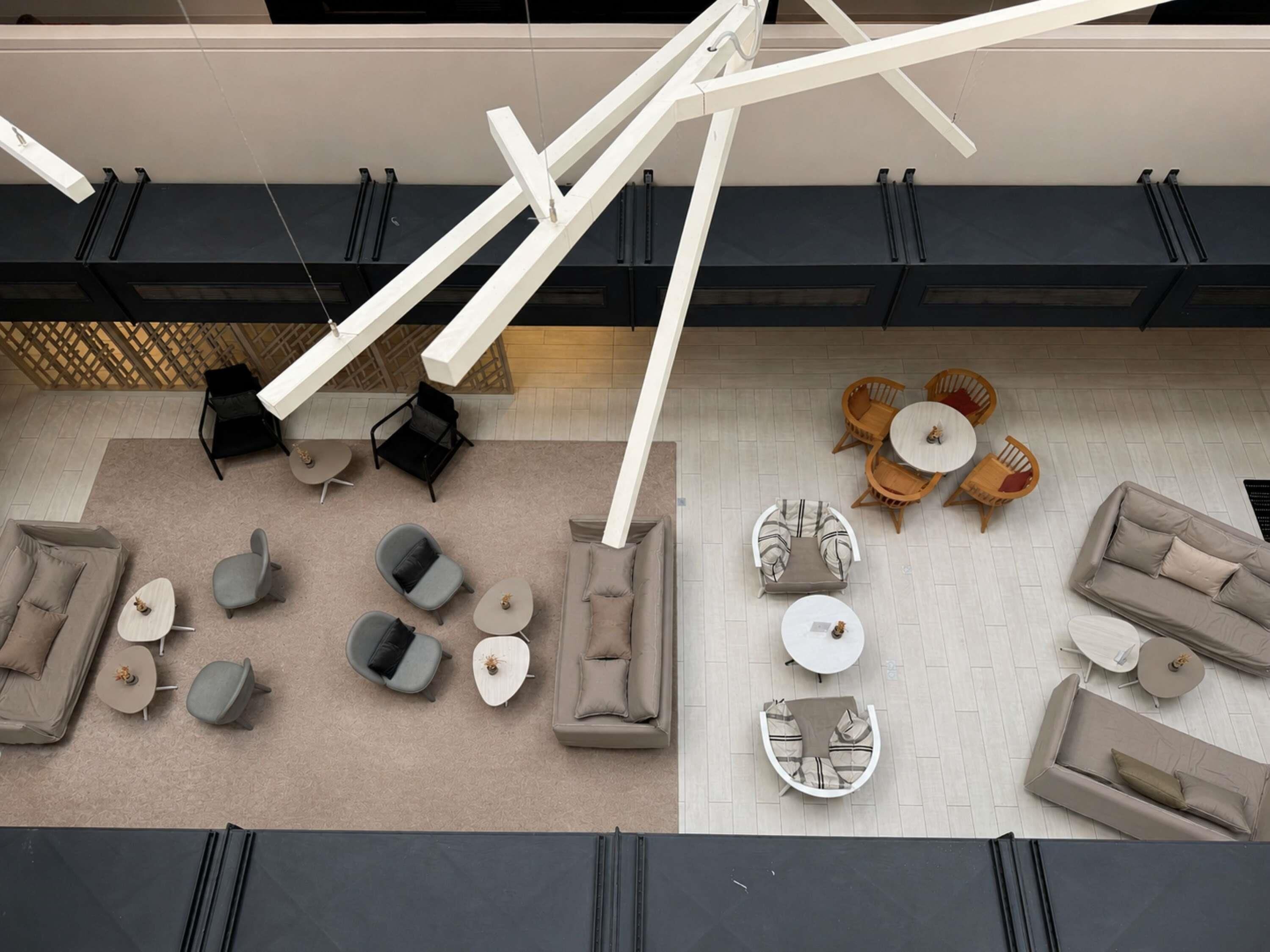 Un interior moderno con un sofá modular, varias sillas, una mesa redonda y una lámpara colgante.