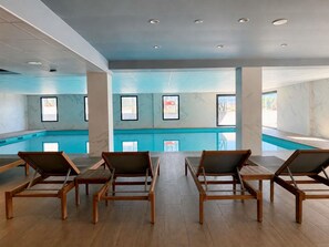 Ein Poolbereich mit Holzliegen, einer blauen Akzentwand und gerahmten Bildern.