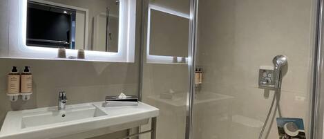 Une salle de bain moderne avec une douche à parois de verre, un meuble-lavabo avec un miroir et un porte-serviettes.