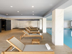 A spa area with wooden loungers, a pool, marble walls, and recessed ceiling lights. - Mercure Hotel & Spa Bastia Biguglia (Biguglia)