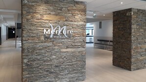 Eine Hotelhalle mit einer Steinsäule, die das Logo 'Mercure Hotels' zeigt.