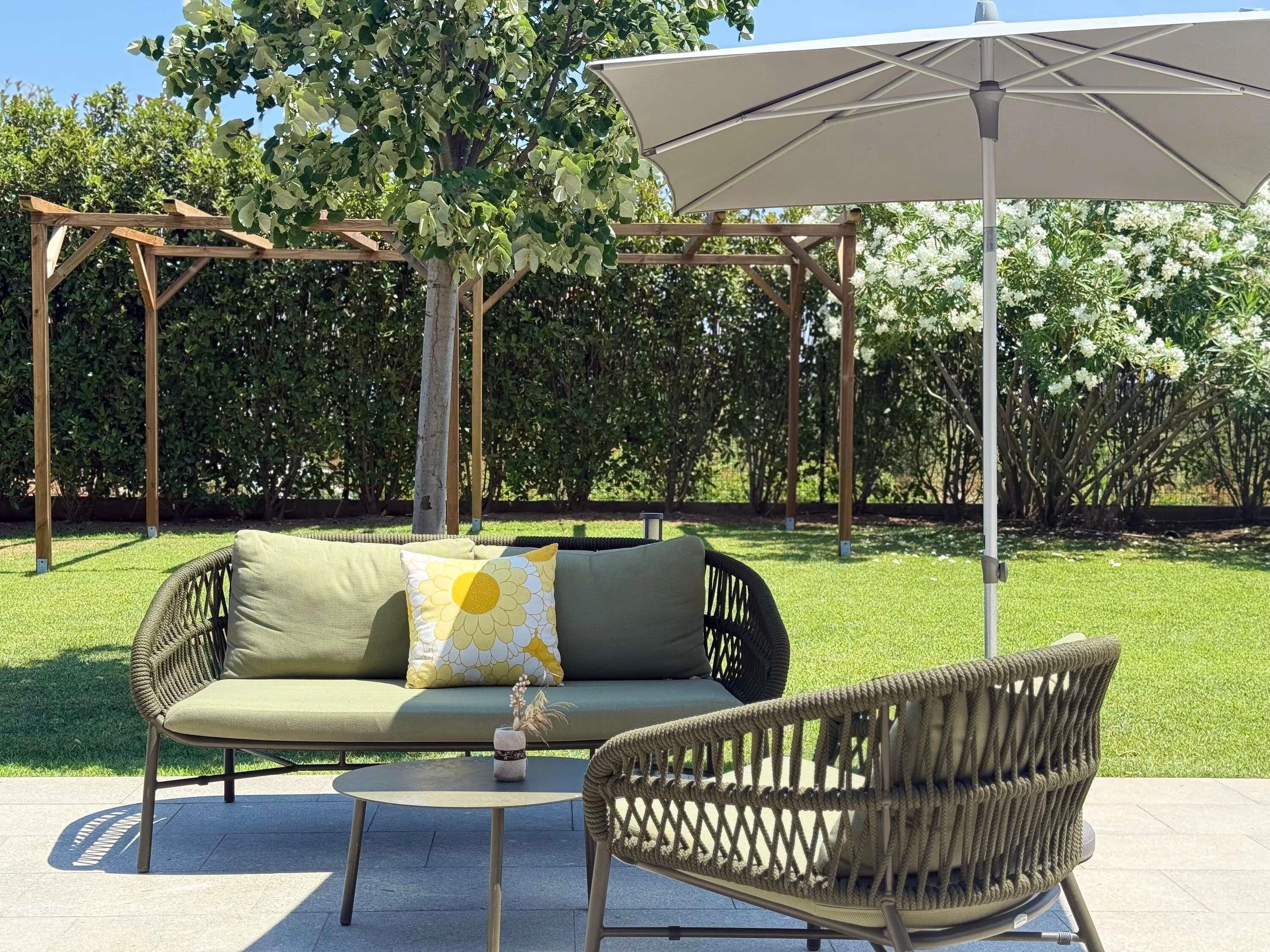 A patio with a wicker sofa, a small round table, and an umbrella.