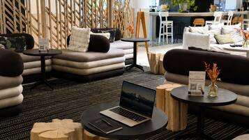 A modern lounge area with sofas, a laptop on a table, and a bar in the background.