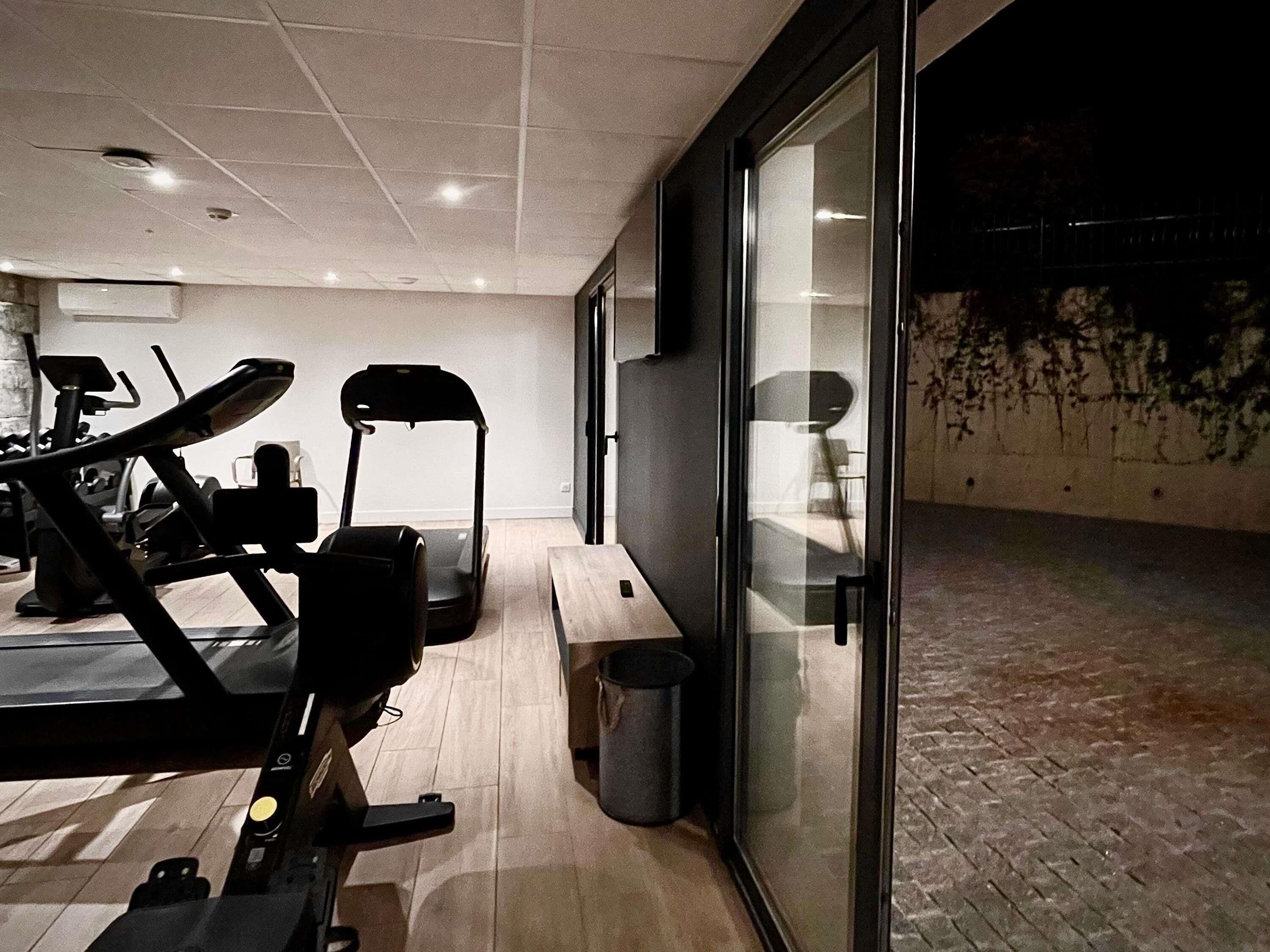 Un gimnasio con equipamiento de ejercicio, cinta de correr y banco.