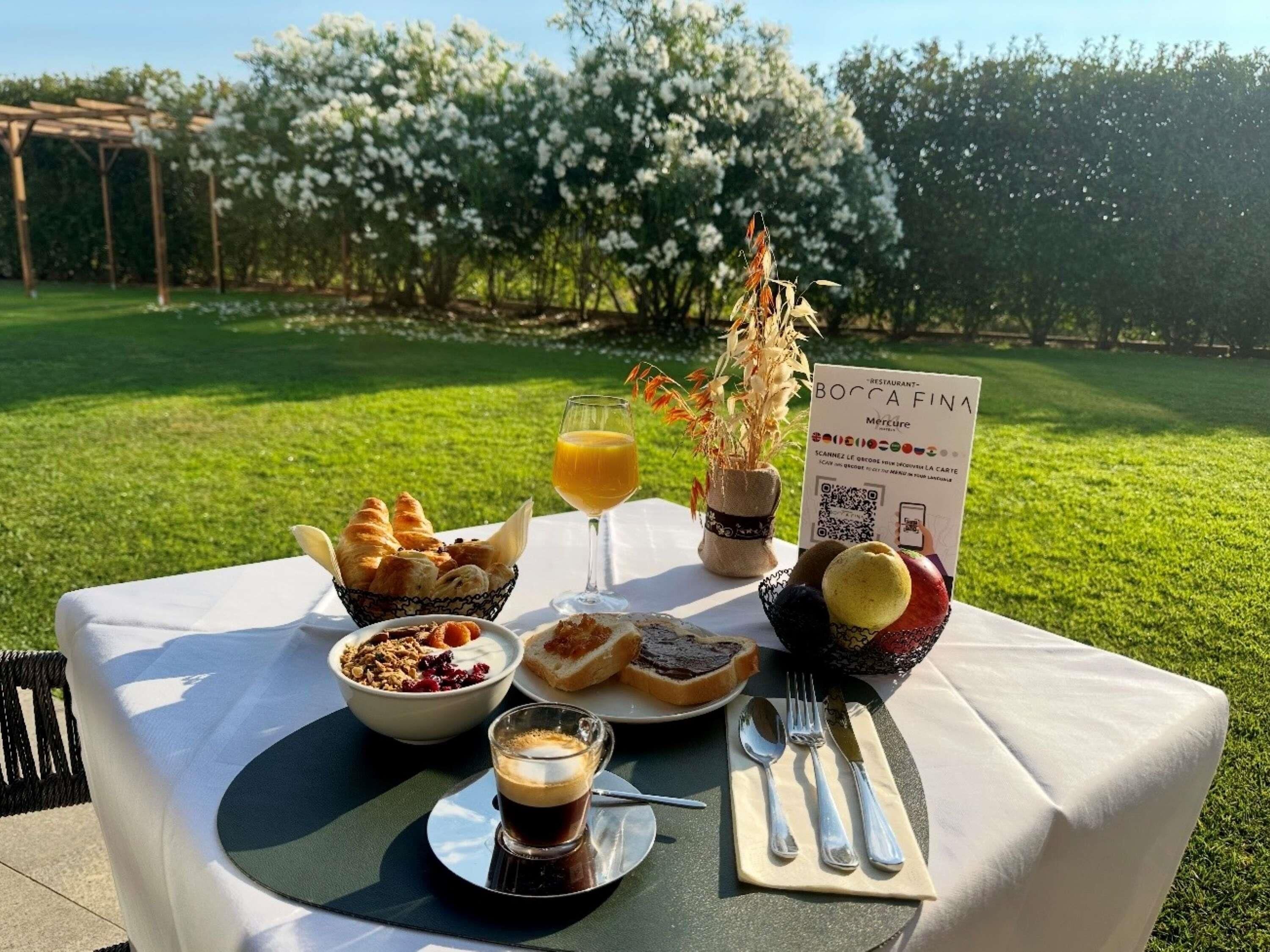 An outdoor dining table with a variety of food items, a QR code menu, and a sign for a restaurant named 'BOCCA FINA'.