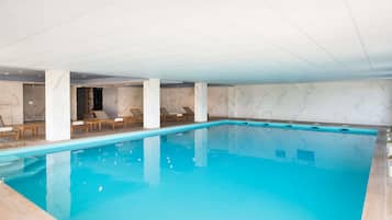 Una piscina techada, sillones reclinables de piscina