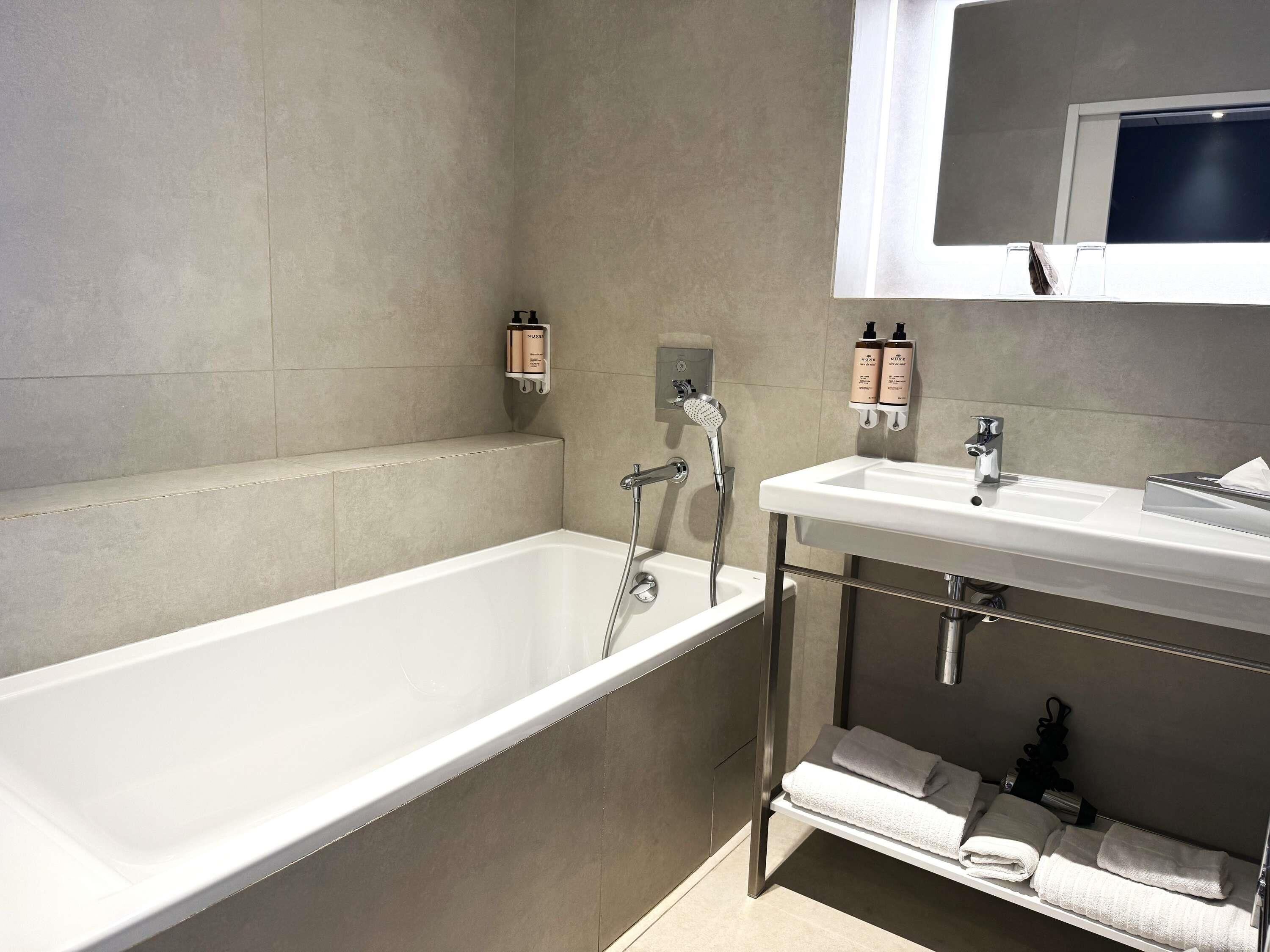 A modern bathroom with a bathtub, a sink, and a towel rack.