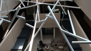 Ein großzügiger Innenbereich mit verschiedenen Sitzgelegenheiten, darunter Sofas und Sessel, und einer hohen Decke mit freiliegenden Trageelementen.