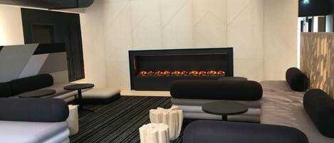 Un área de estar moderna con chimenea, sofás y una mesa de centro.