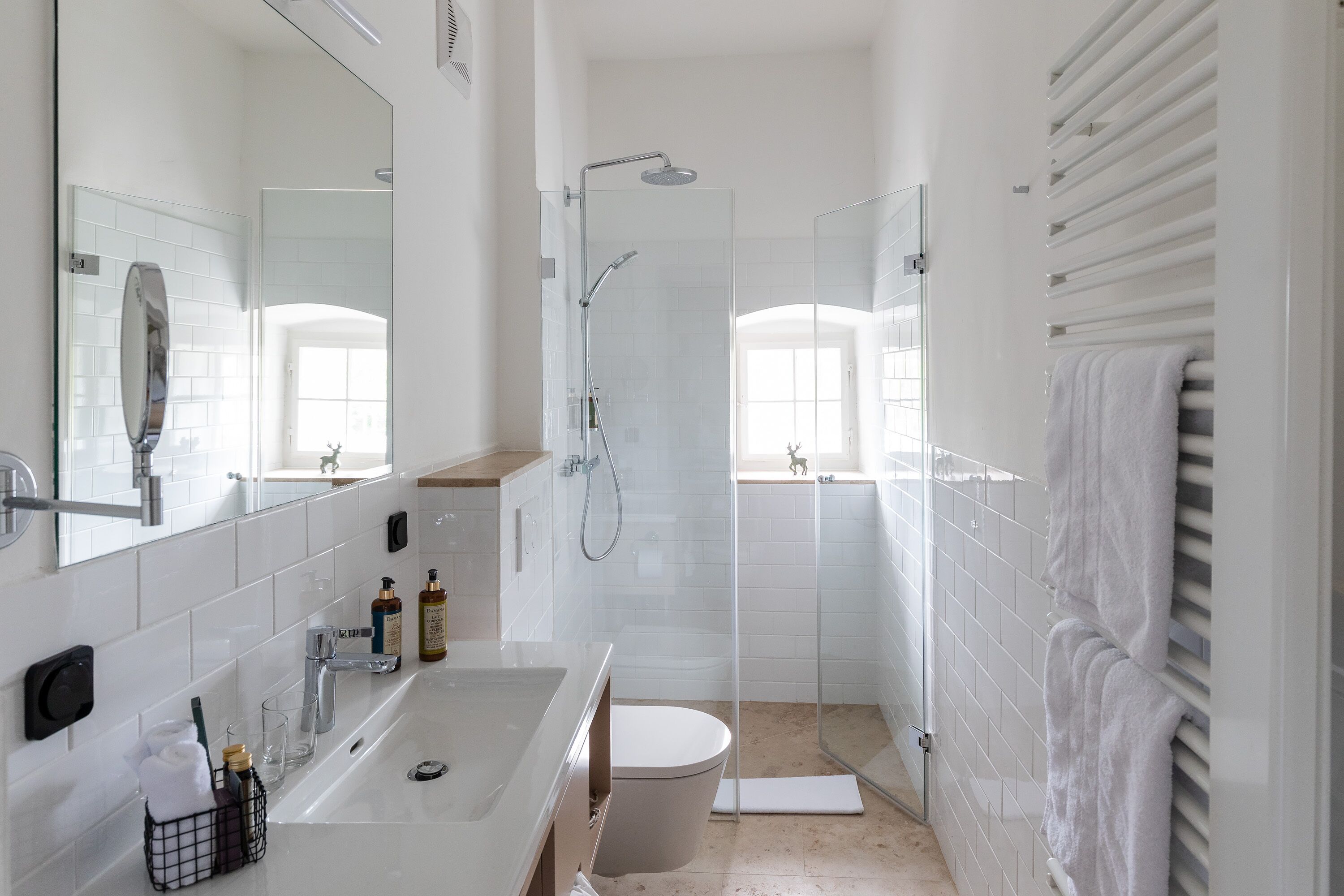 Et moderne badeværelse med en glasafskærmet brusekabine, en hvid vask og et toilet.