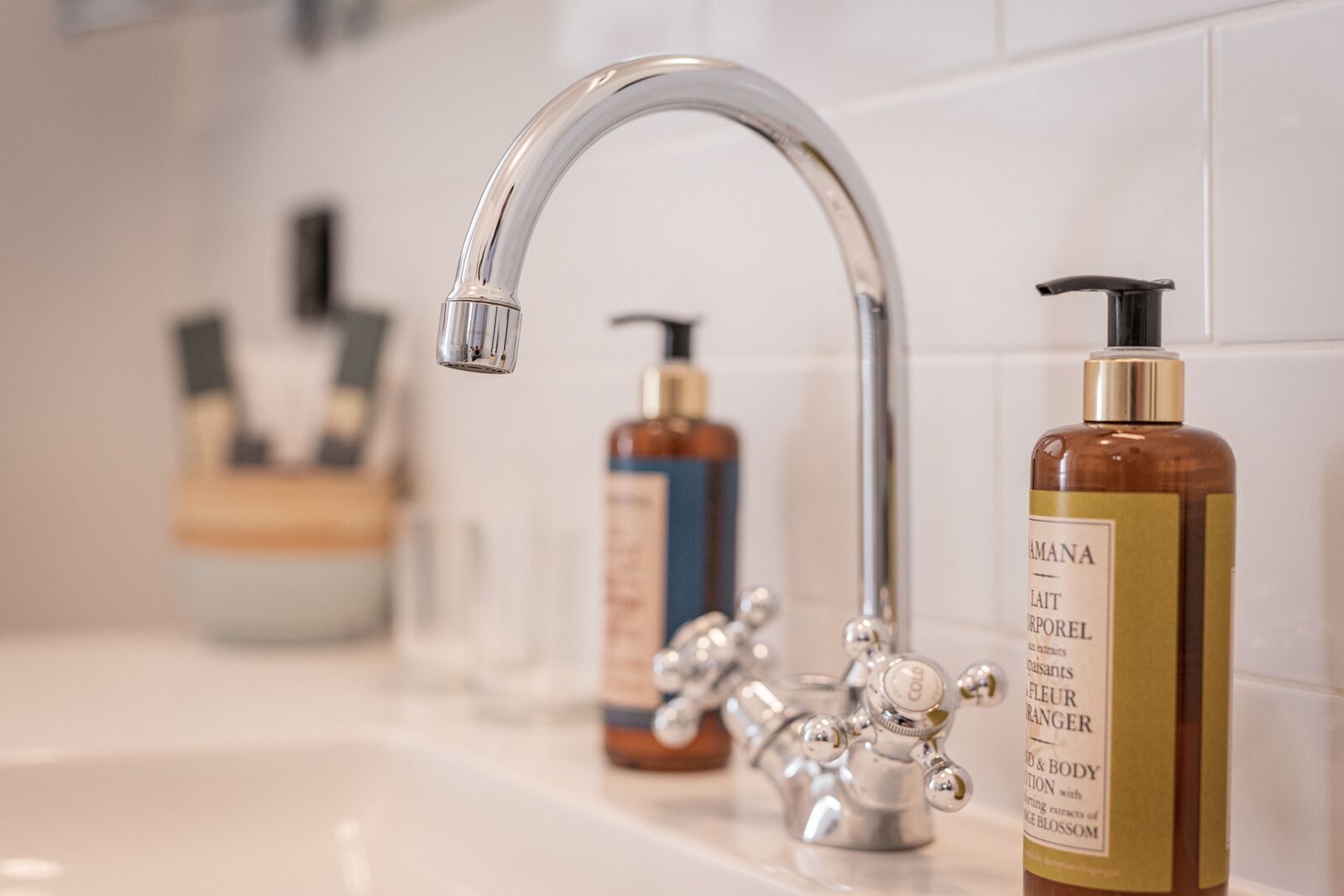 Un baño con un grifo moderno y dos botellas de productos de cuidado corporal sobre el lavamanos.