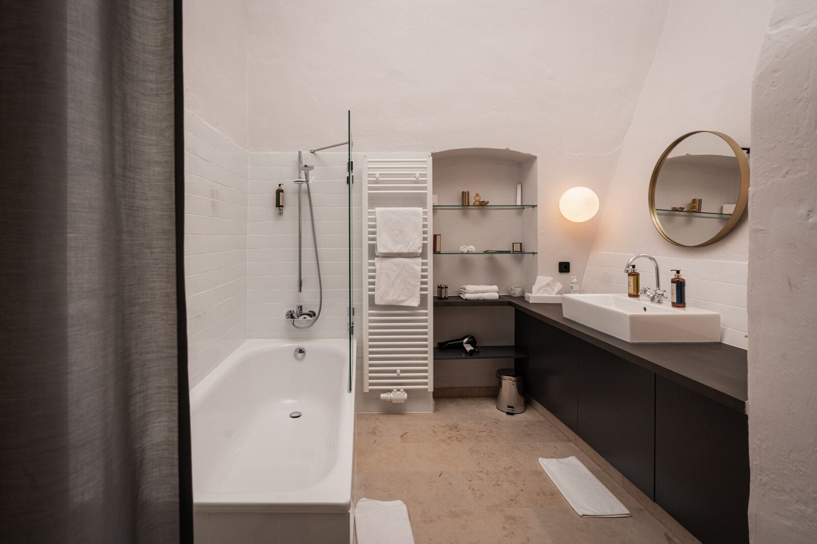 Un baño moderno con bañera, ducha, tocador con lavamanos y espejo.