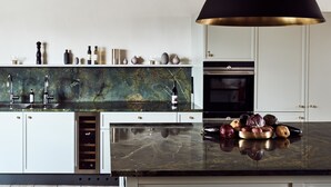 A modern kitchen with a marble countertop, stainless steel appliances, and a black pendant light. - Boutique Hotel Zum Oberjäger (Lackenbach)