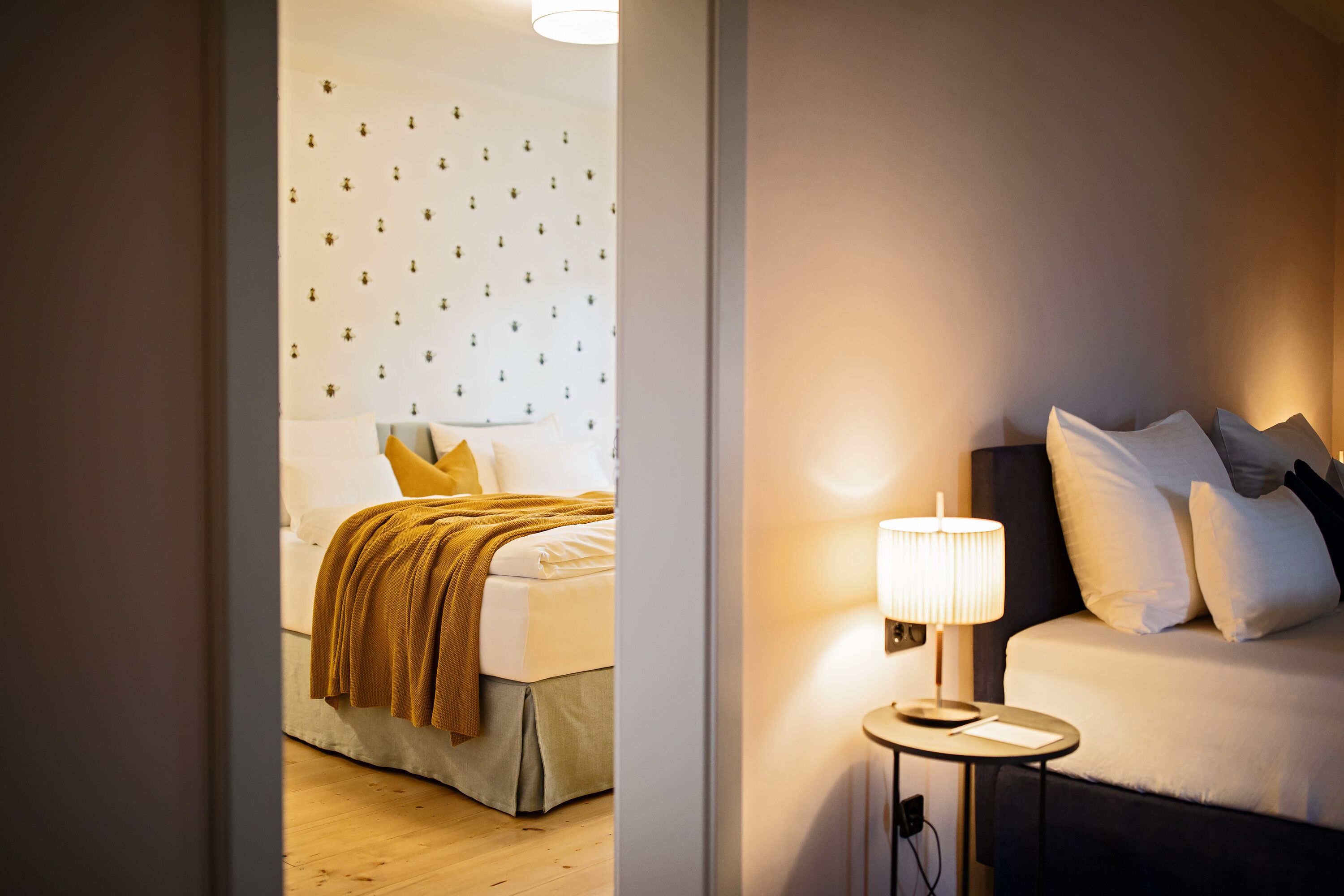 Una habitación de hotel con cama, mesita de noche y una pared decorada con pequeños iconos.