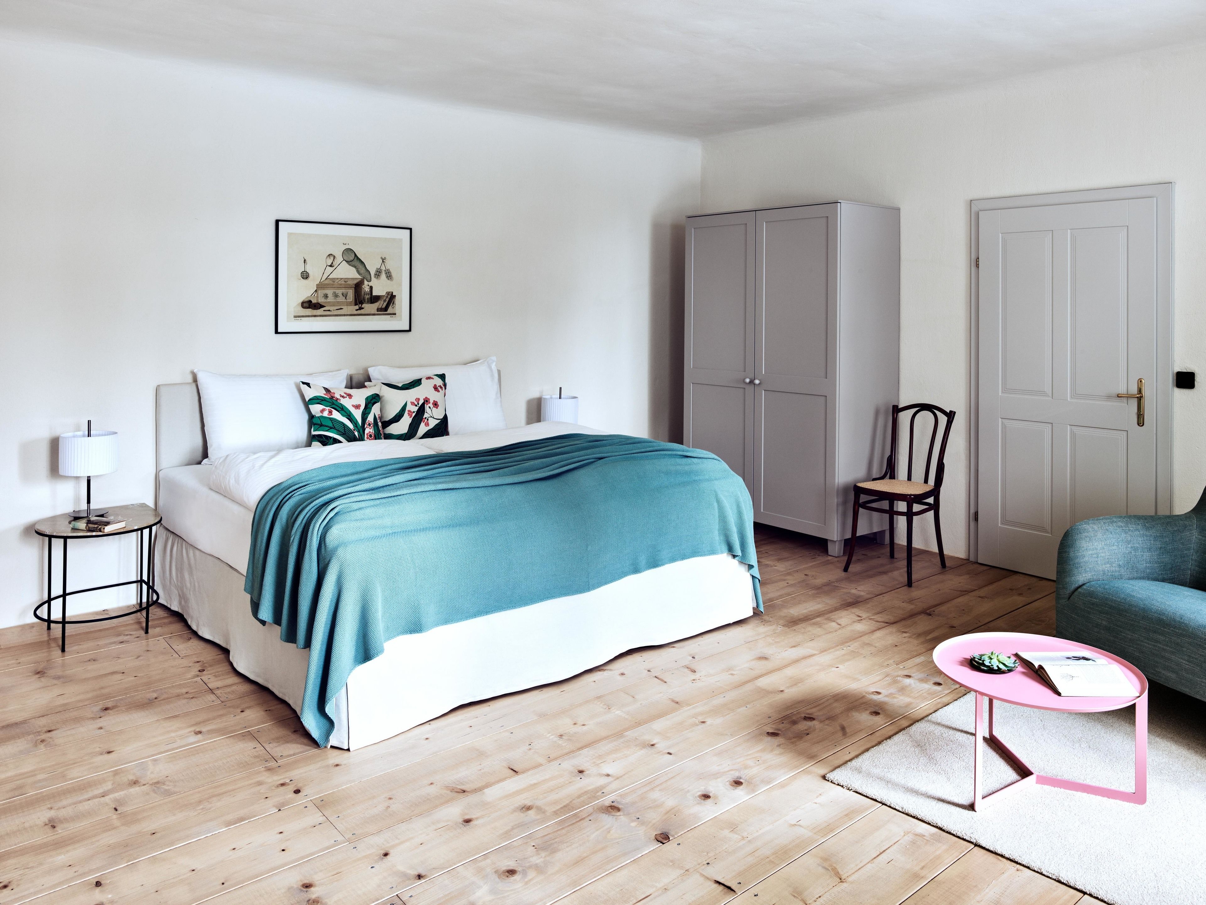 Une chambre à coucher comprenant un lit, une table de chevet, une chaise, une armoire et une porte.