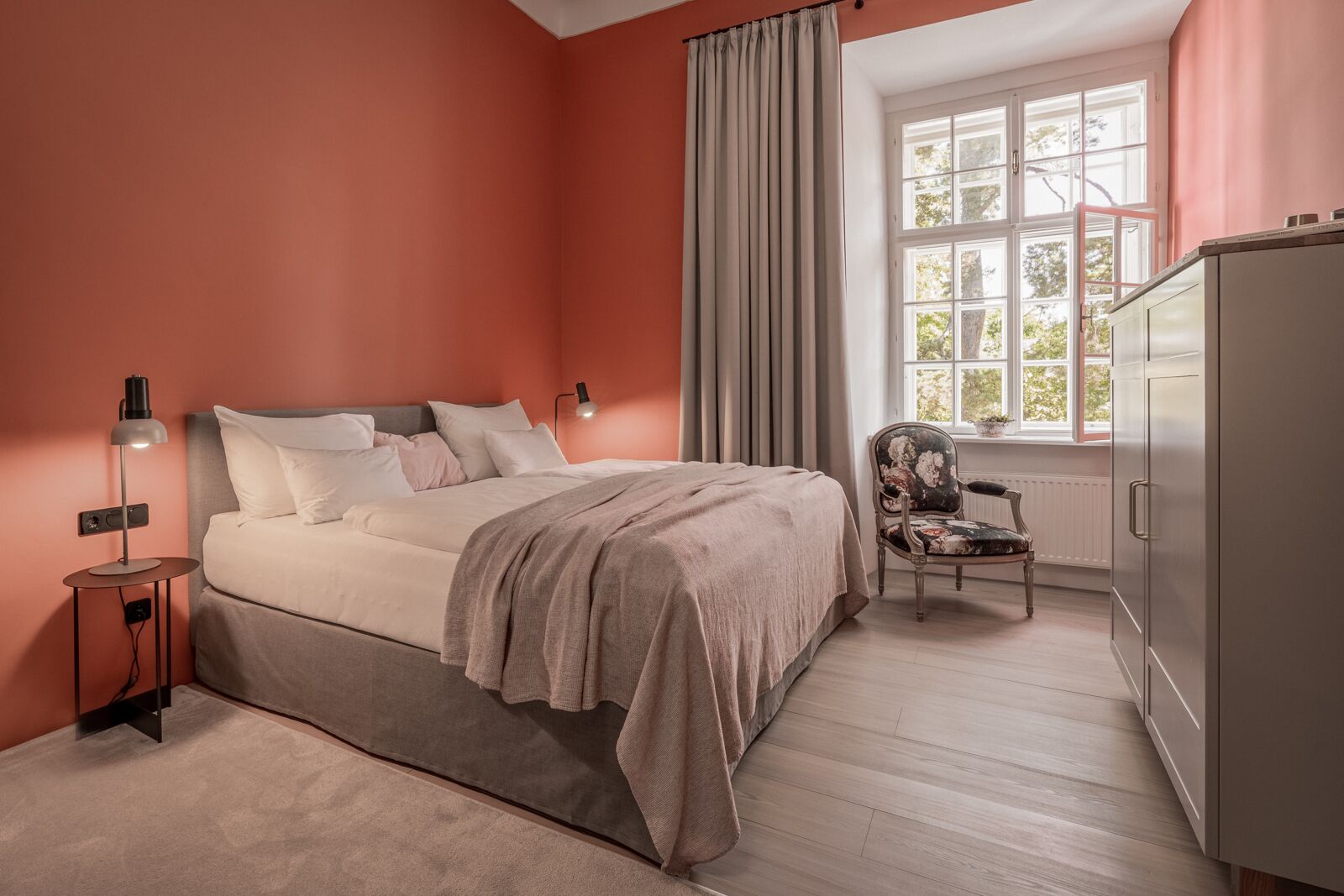 Un dormitorio con cama, una silla, una lámpara y un armario.