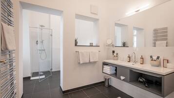 Ein modernes Badezimmer mit Glasdusche, Waschtisch inklusive Spiegel und einem Handtuchhalter.