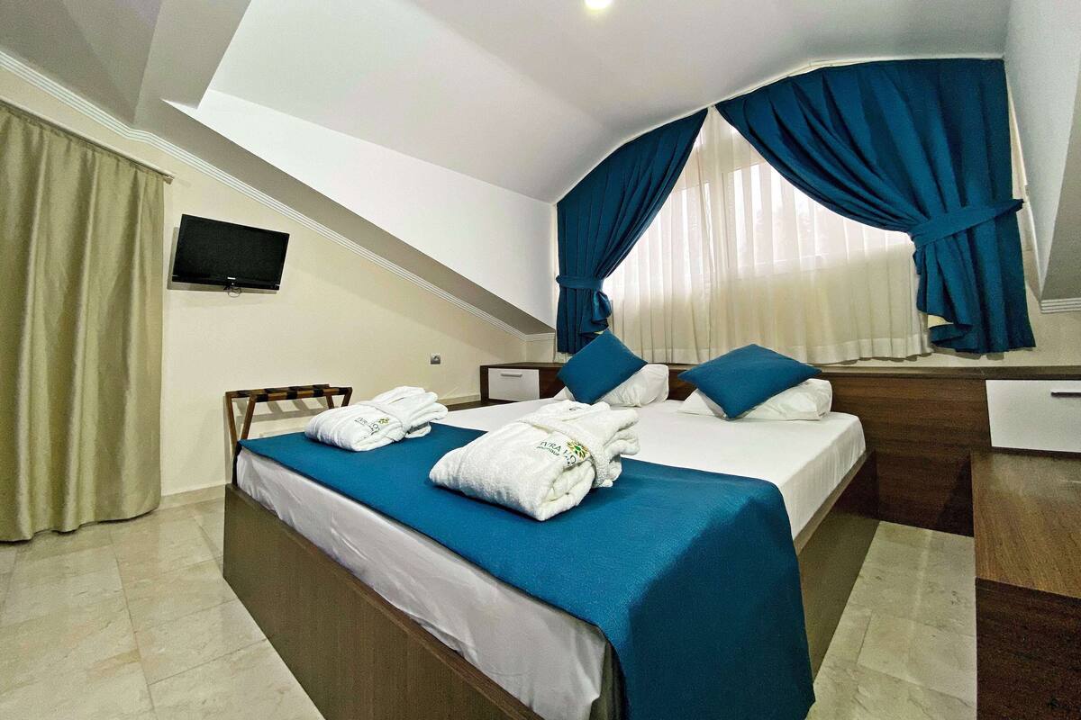 Une chambre d’hôtel avec deux lits, un téléviseur fixé au mur et un bureau.