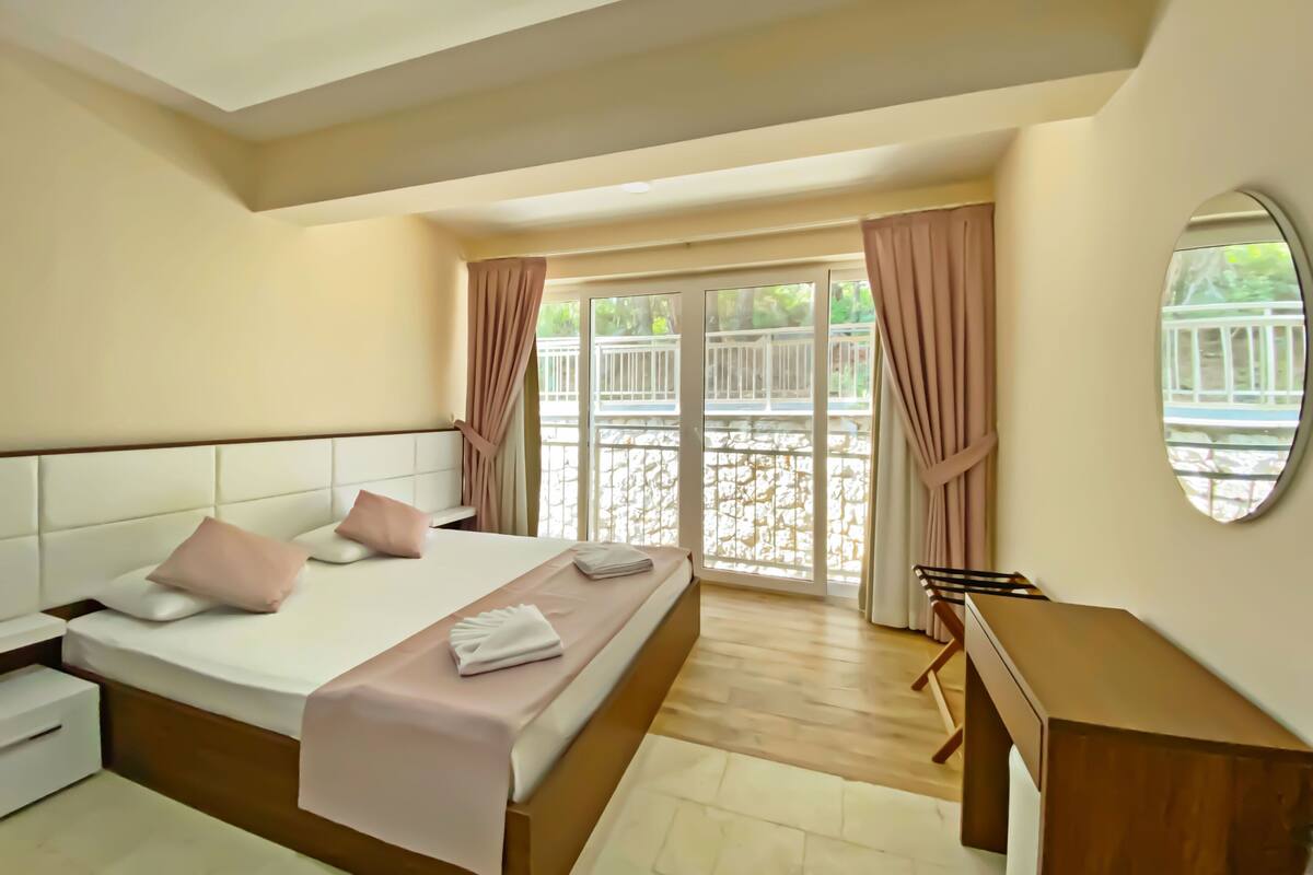 Une chambre à coucher comprenant un lit, des tables de chevet, un bureau et donnant sur un balcon extérieur.