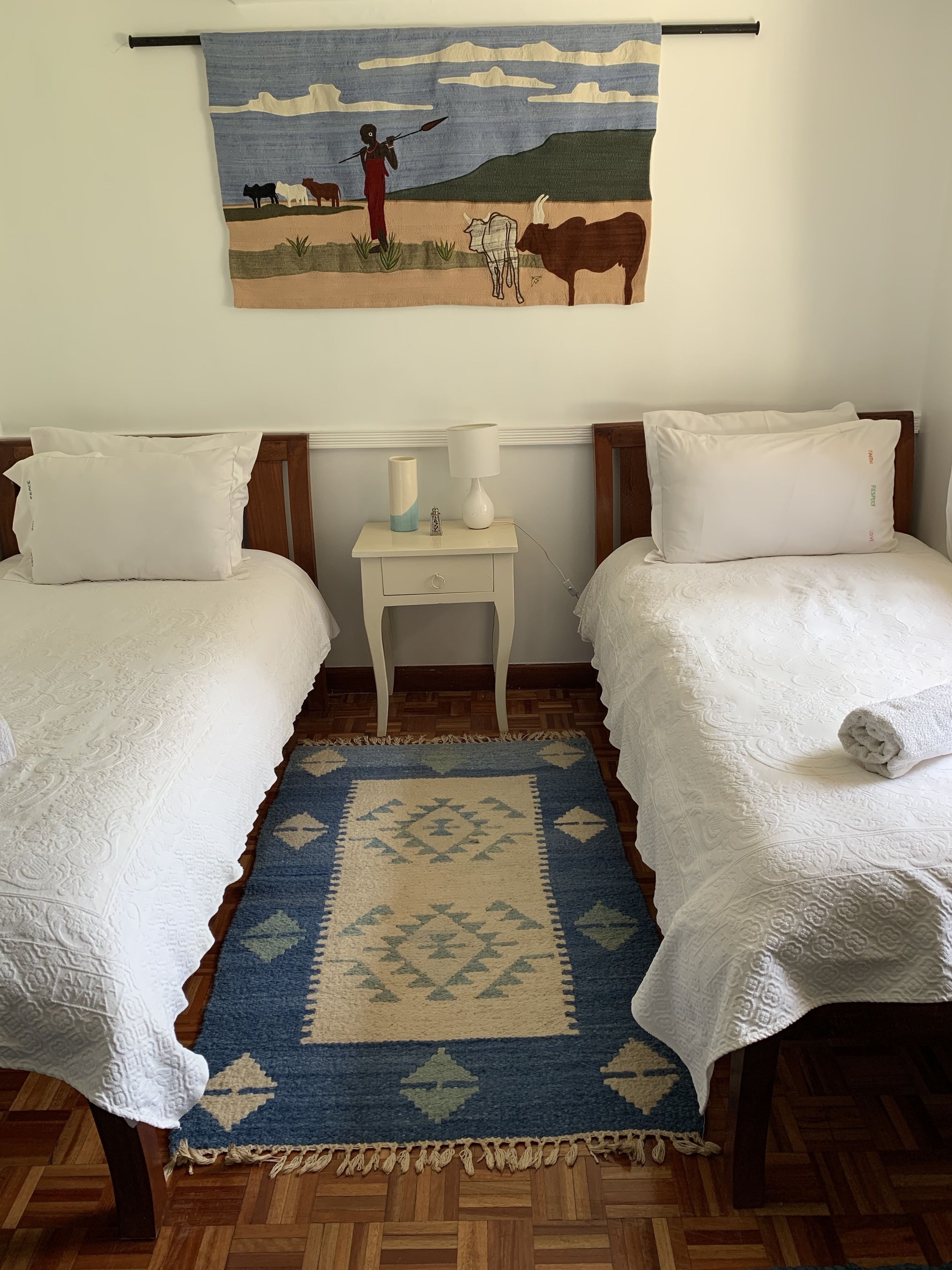 Une chambre avec deux lits, une table de chevet, une lampe et une décoration murale.