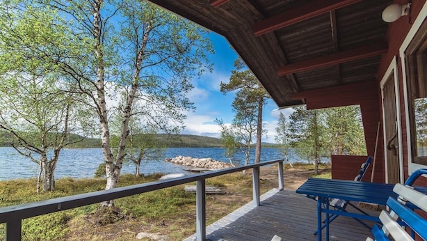 Een houten terras met banken, met uitzicht op een meer, omringd door bomen.