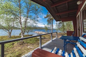 A wooden deck with benches overlooking a lake, surrounded by trees. - Ukonjärven Holiday Village (Inari)