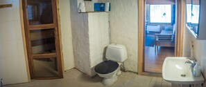 A small bathroom with a toilet, sink, and a wooden door.