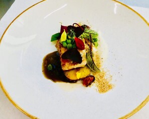 Un plato blanco con borde dorado, que contiene un guiso de diferentes verduras y salsa.