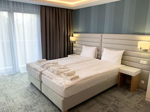 Una habitación de hotel moderna con una cama grande, una mesita de noche y un cabecero con iluminación integrada.