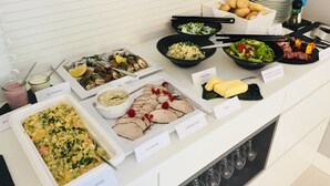 A buffet with various dishes including a salad, rice, and sliced meat, with labels in a foreign language. - Hotel Hel (Hel)