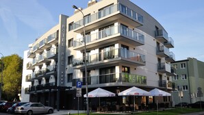 A multi-story hotel with balconies, outdoor seating, and a parking sign. - Hotel Hel (Hel)