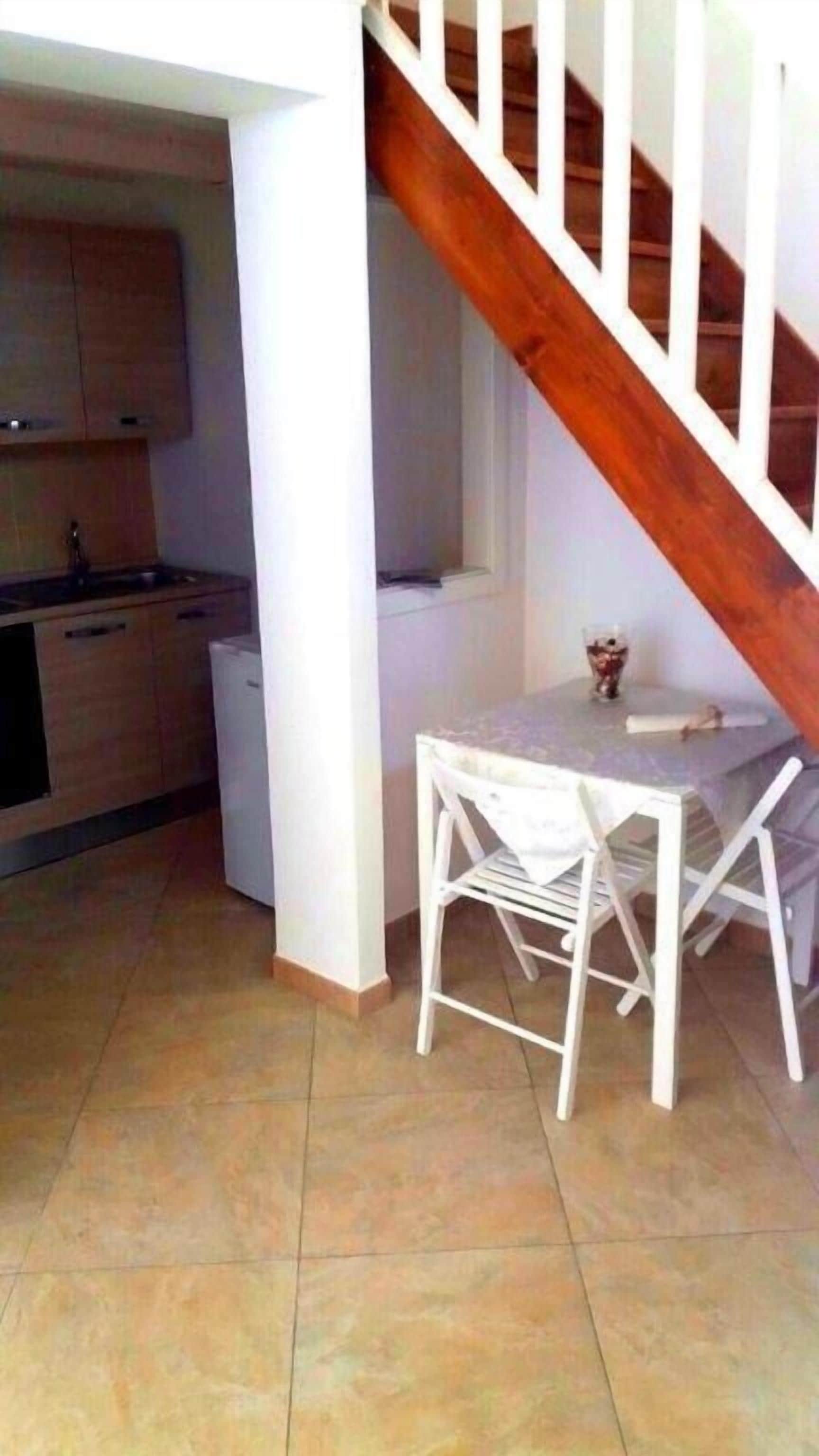 Eine Küche mit Holzausstattung, einem weißen Kühlschrank und einem Esstisch mit weißen Stühlen.