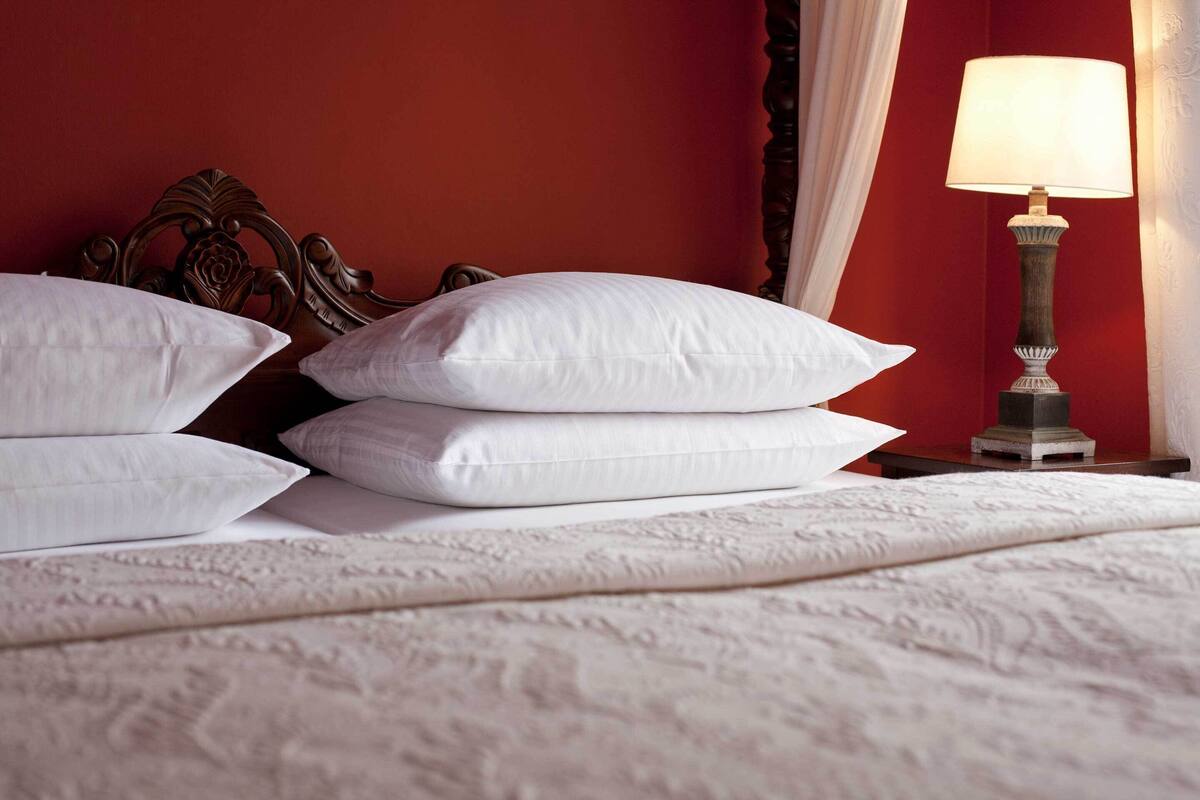 A neatly made bed with white pillows and a textured white bedspread.