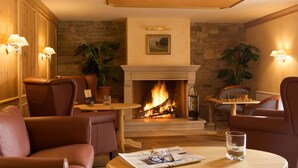 A cozy room with leather chairs, a fireplace, and a chess table. - Allgäuer Kräuteralm (Oberstaufen)