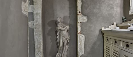 A bathroom with a marble statue, a sink, and a cabinet.