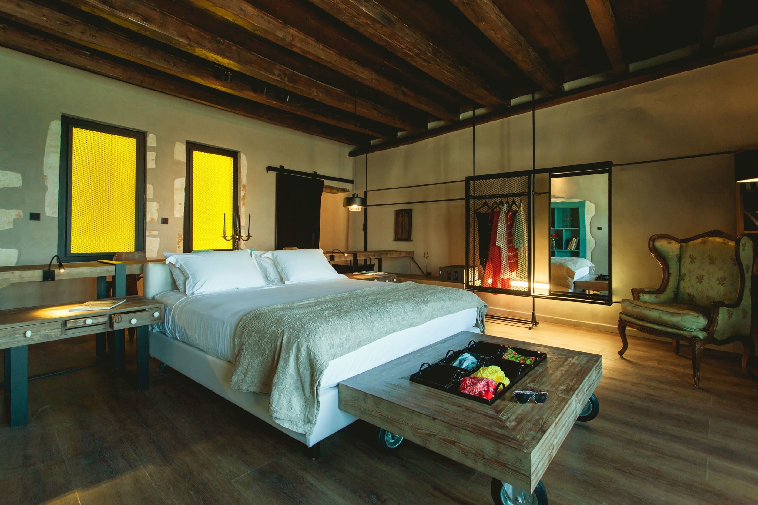 A bedroom with a large bed, a wooden nightstand, a desk, and a chair.