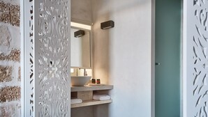 Bany amb un lavabo blanc, mirall i prestatges amb tovalloles.