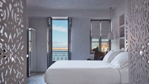 A bedroom with a large bed, a view of the sea, and a balcony with curtains.