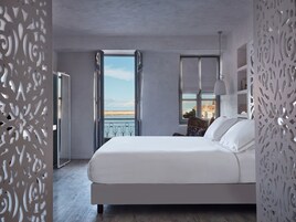 A bedroom with a large bed, a view of the sea, and a balcony with curtains.