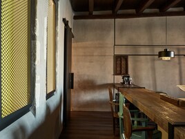 A dining area with a wooden table, chairs, and a hanging light fixture.