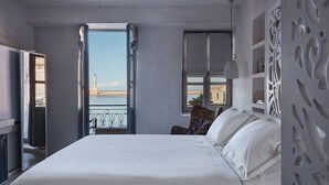 Habitació d'hotel amb un llit gran, vista al mar i un balcó amb barana.