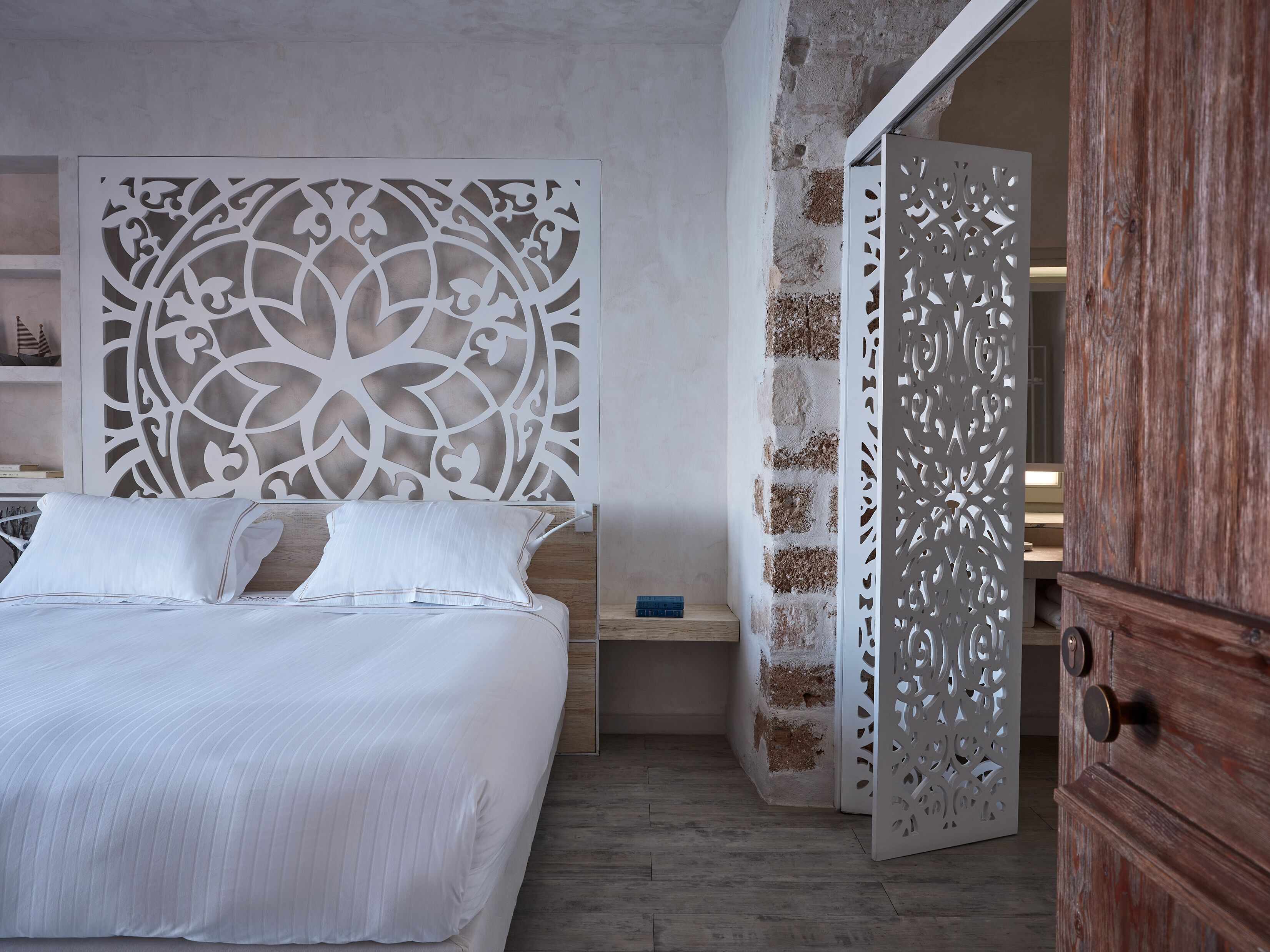 Ein Schlafzimmer mit einem Bett, einer Zierverkleidung an der Wand und einem Holzschrank.