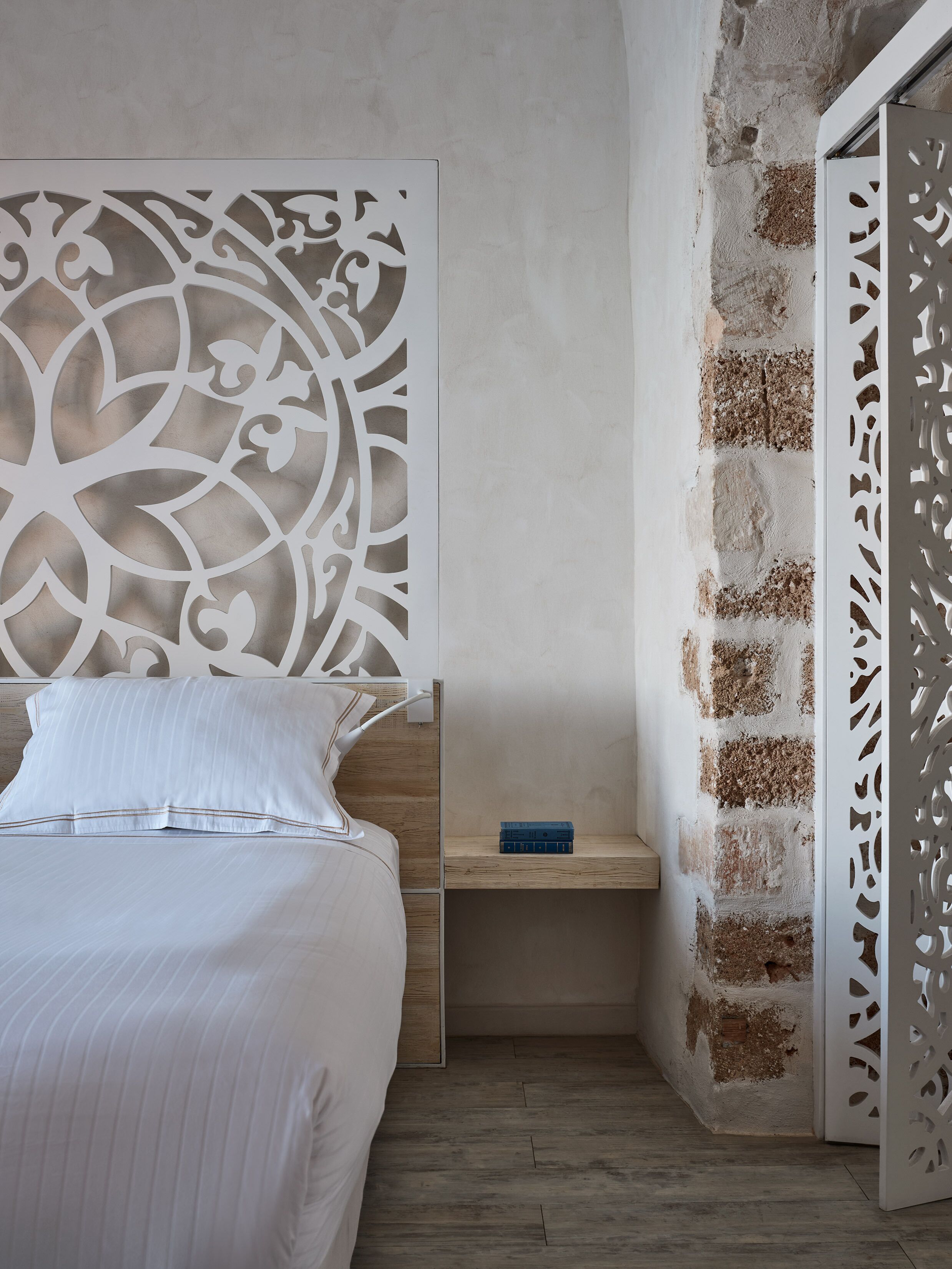 A bedroom with a bed, a nightstand, and a decorative wall panel.