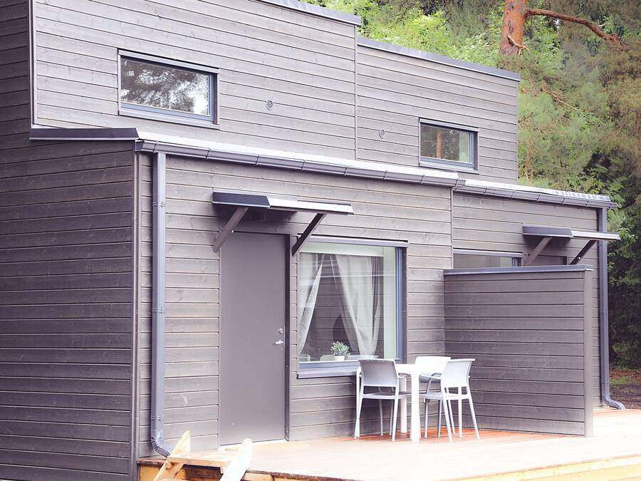 A modern house with a deck, two windows, and a door.